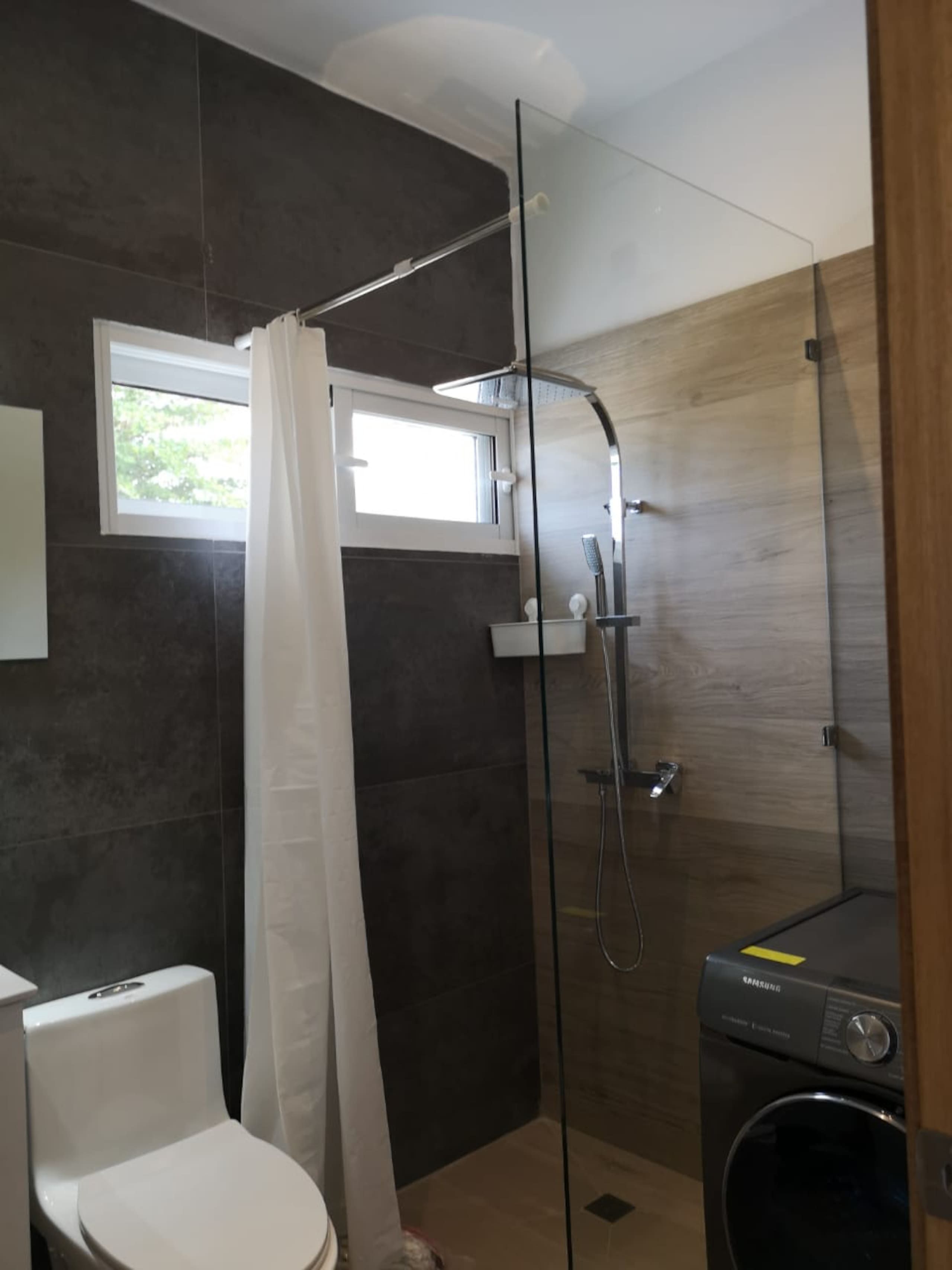 Un baño moderno con cabina de ducha de vidrio, inodoro y lavadora.