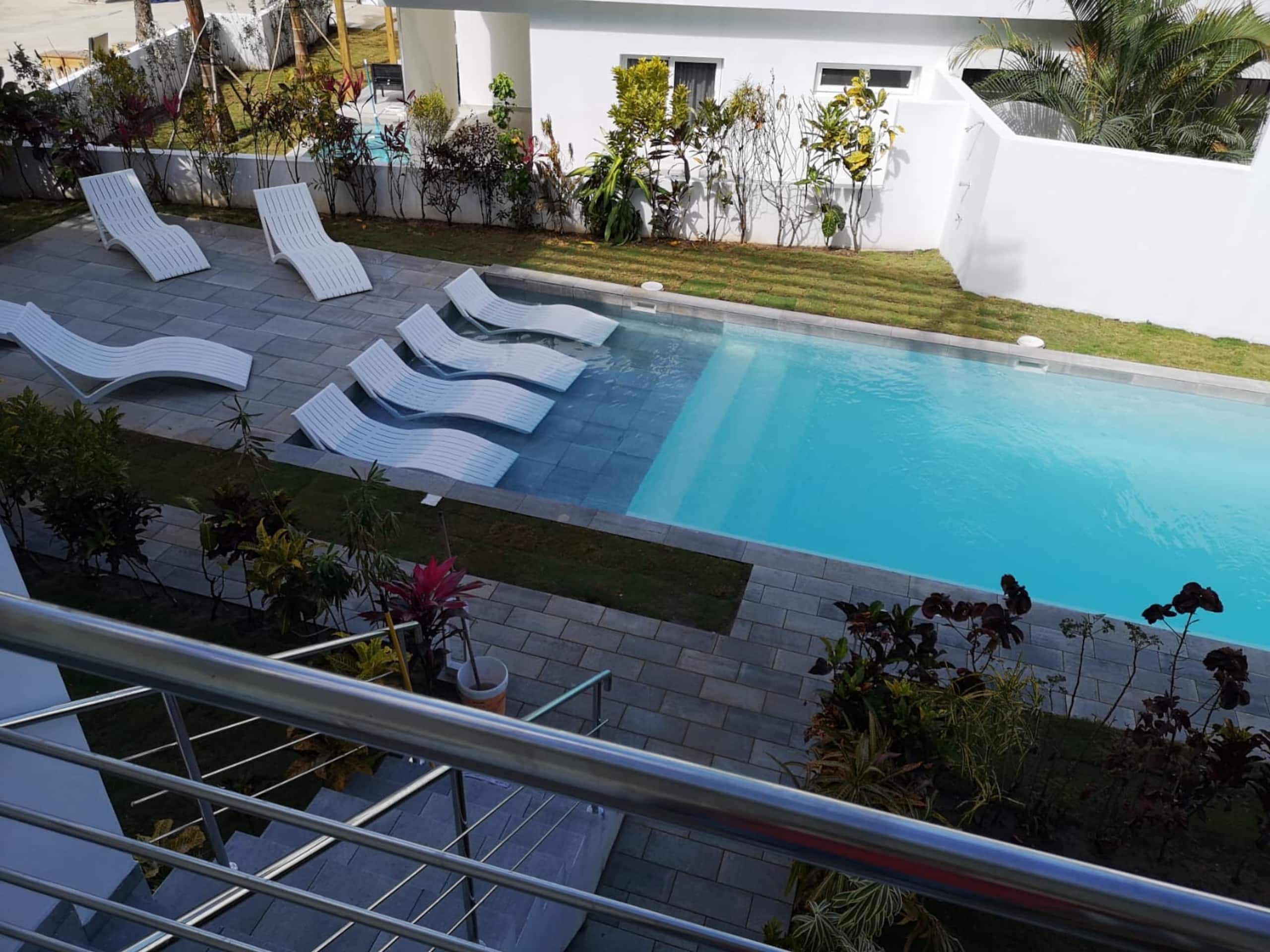 Una piscina con sillones de descanso y un césped cuidado.