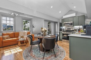 A modern kitchen with stainless steel appliances, a dining area with a round table and chairs, and a cozy living space with a sofa and a coffee table. - Historic Bay Village / Cozy 1BR Getaway (Boston)