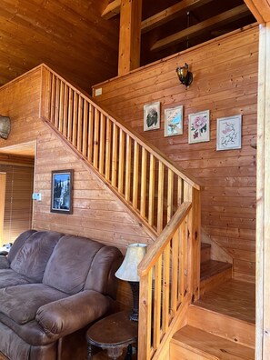 Eine HolztTreppe mit einer gepolsterten Bank am unteren Ende, einer Lampe und gerahmten Pflanzenbildern an der Wand.