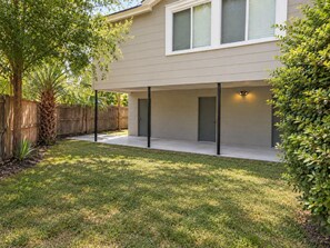A modern two-story house with a covered patio area, a wooden fence, and a well-maintained lawn. - Park Avenue Retreat | Near Downtown (Savannah)
