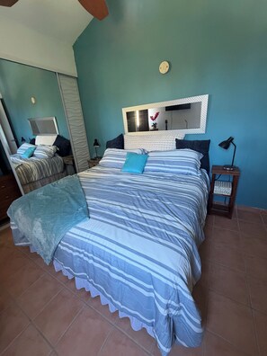 A bedroom with a bed, a bedside table, a nightstand, a mirror, and a wall-mounted light fixture. - 3 Bedroom beachfront penthouse loiza Puerto Rico (Loíza)