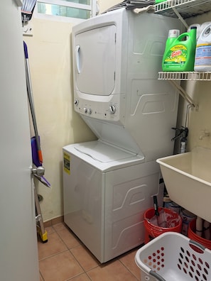 A compact laundry area with a washing machine, a mop, and cleaning supplies. - 3 Bedroom beachfront penthouse loiza Puerto Rico (Loíza)