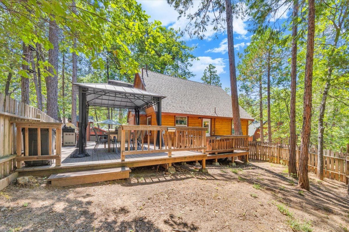A cabin with a deck, surrounded by trees.