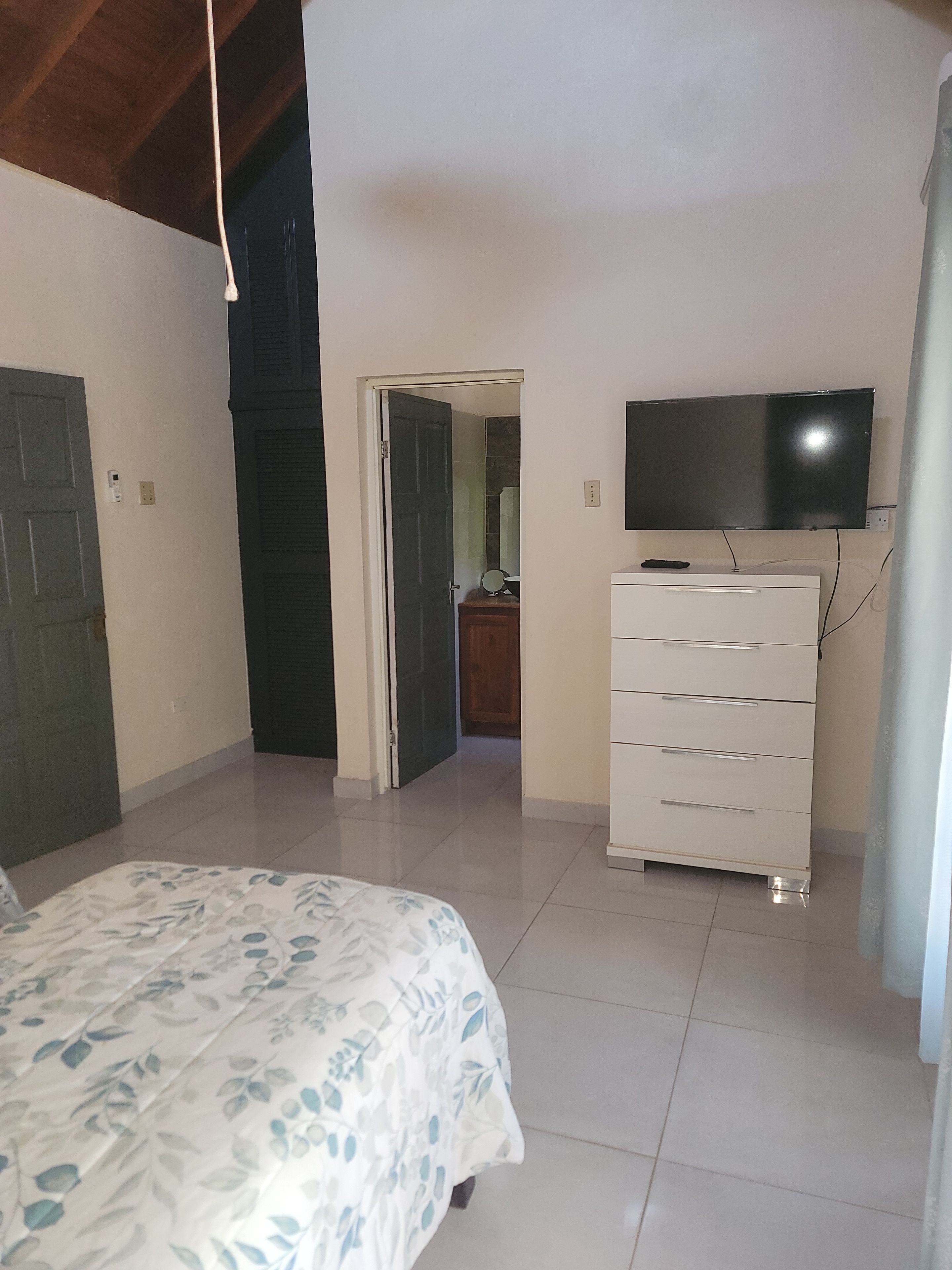 Una camera da letto con un letto, una cassettiera, un televisore e una porta che dà su un'altra stanza.