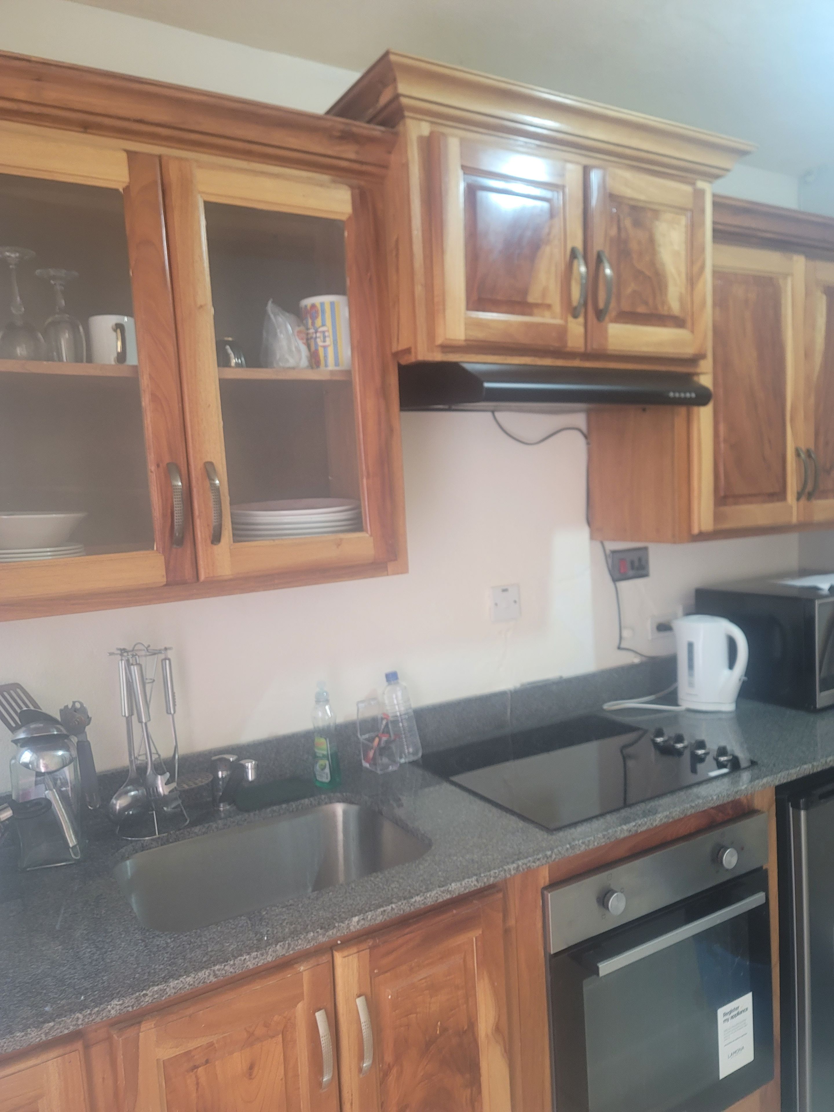 Una cucina con mobili in legno, lavello in acciaio inossidabile, fornello e microonde.