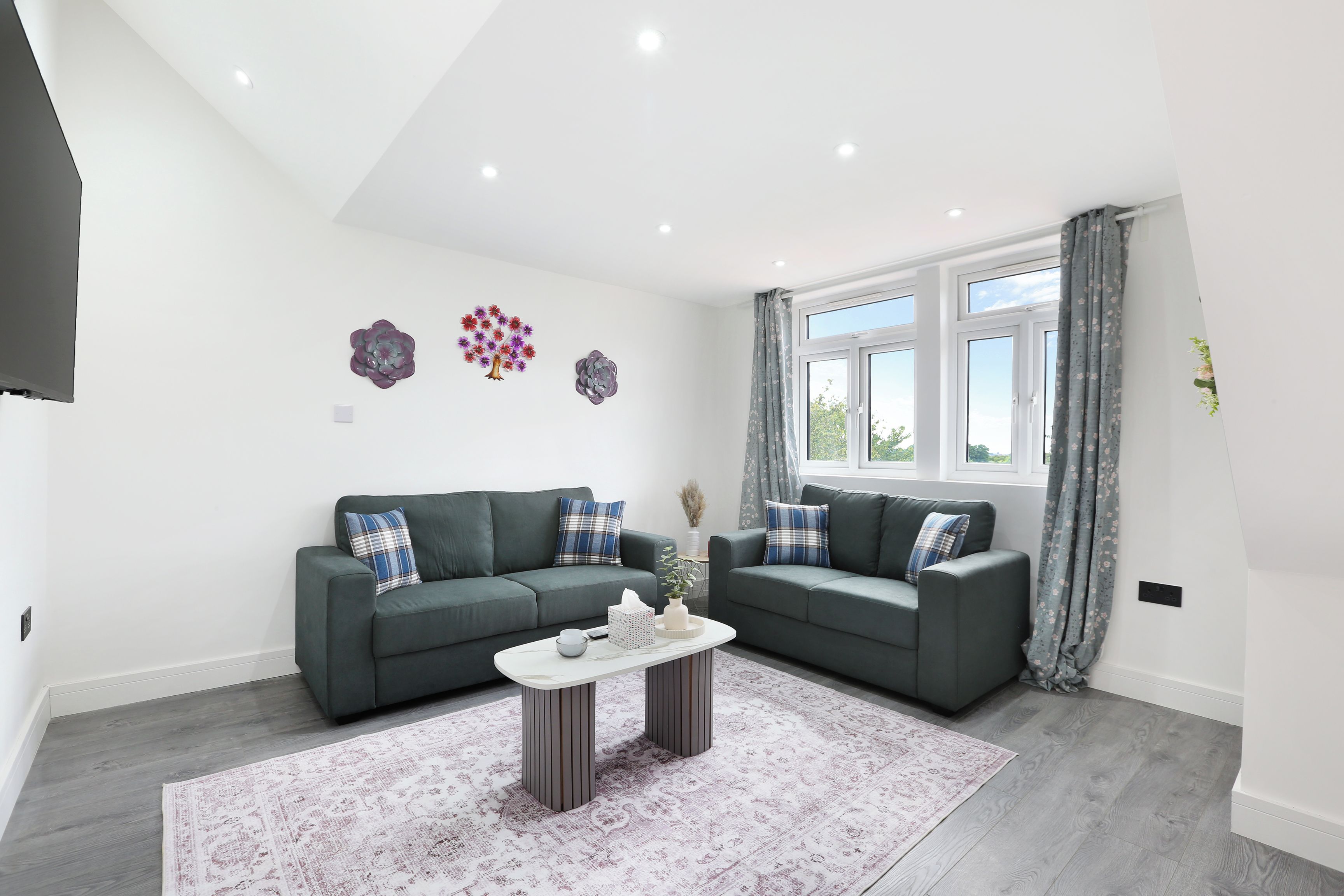 A modern living room with two grey sofas, a white coffee table, and decorative wall art.