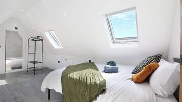 A modern bedroom with a skylight, a bed with pillows, a hanging shelf, and a radiator.