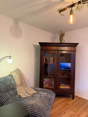 Ein gemütliches Wohnzimmer mit einem Holzkabinett, einer Couch und einem Tisch.