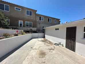 A residential building with a concrete patio, a metal gate, and a small garden area with a toy car. - Freshly Updated 2 Bed 1 Bath Unit With Quick Beach Access! (San Clemente)