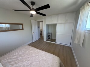 A bedroom with a bed, a ceiling fan, a walk-in closet, and a window with curtains. - Freshly Updated 2 Bed 1 Bath Unit With Quick Beach Access! (San Clemente)