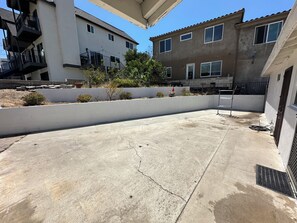 A concrete patio area with a white wall and a metal railing. - Freshly Updated 2 Bed 1 Bath Unit With Quick Beach Access! (San Clemente)