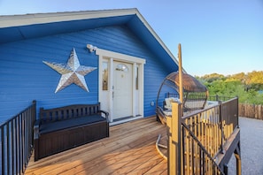 A building with a blue exterior, a white door, a star decoration, a wooden deck, and a swing chair.
