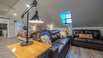 A spacious living room with a large leather sofa, a wooden coffee table, and a modern floor lamp.