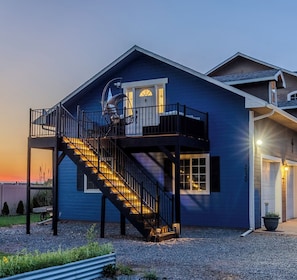 Ein zweistöckiges Haus mit Balkon, Treppe und Garage.