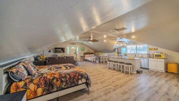 Um amplo loft com uma cama grande, uma cozinha e um espaço de refeições.