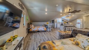 A spacious loft with a high ceiling, a dining area, a kitchen, and a living room with a sofa and a coffee table. - Kieckhaefer Acres - Honey House (Grand Junction)