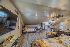 A spacious loft with a high ceiling, a dining area, a kitchen, and a living room with a sofa and a coffee table. - Kieckhaefer Acres - Honey House (Grand Junction)