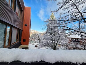 A building with a red facade and large windows, surrounded by snow-covered trees and a clear sky. - #7 Modern Loft with Fast WiFi, Great for Remote Work. 300 m from the Lake (San Carlos de Bariloche)
