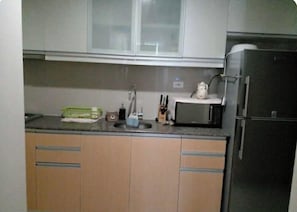 A kitchen with a sink, a microwave, and a refrigerator. - One Uptown Residence 30H (Taguig City)