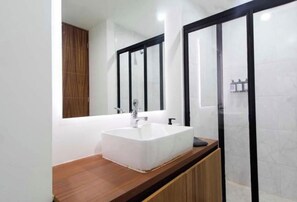 Un bany modern amb un mirall gran, un lavabo blanc i un tocador de fusta.