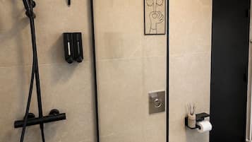 A modern bathroom with a shower, toilet, and a towel rack.