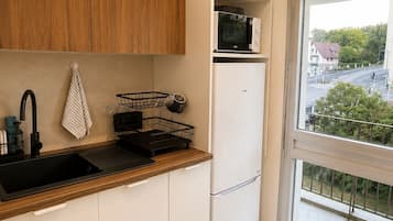 A modern kitchen with a wooden countertop, a sink, a microwave, and a refrigerator.