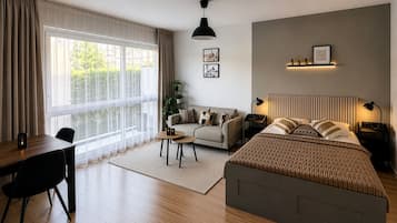 Et moderne soveværelse med en stor seng, en sofa, et skrivebord og et vindue med gardiner.