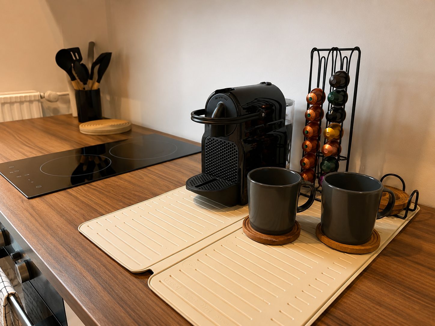 A kitchen counter with a coffee maker, two mugs, a knife holder, and a spatula set.