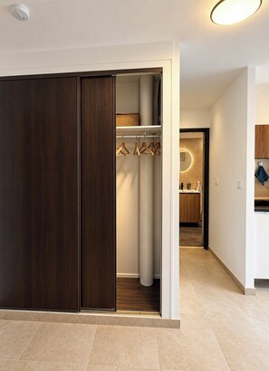 A modern interior with a wooden wardrobe, a hanging closet, and a kitchen area. - Elegant studio apartment with a balcony and parking in Metz (Metz)