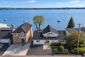 A residential area with houses, a driveway, and a body of water with boats.