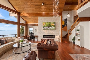 A spacious living room with a leather sofa, a round coffee table, and a fireplace.