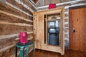 A wooden cabin interior with a kitchenette, a coffee machine, and a door. - Historic Cabin w/King Bed + Walk to Wineries! (Fredericksburg)