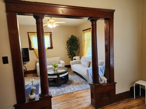 A living room with a wooden-framed doorway, a ceiling fan, a white sofa, a round coffee table, and a potted plant. - Simple & Cozy Cleveland Getaway (Cleveland)