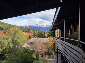 Ein hölzerner Balkon mit Blick auf eine gebirgige Landschaft und Herbstlaub.