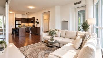A modern living room with a sofa, coffee table, and a view of the kitchen.