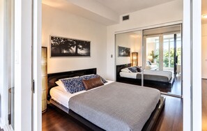 A modern bedroom with a large bed, a bedside table, a mirror, and a painting on the wall. - Spectacular Presidential Loft - Downtown Toronto (Toronto)