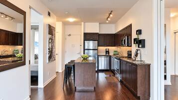 A modern kitchen with dark wood cabinets, stainless steel appliances, and a central island with stools.