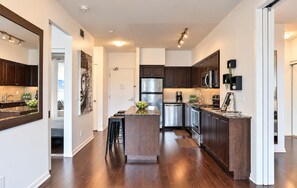 A modern kitchen with dark wood cabinets, stainless steel appliances, and a central island with stools. - Spectacular Presidential Loft - Downtown Toronto (Toronto)