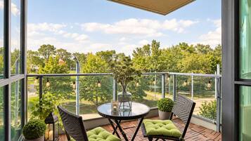 A balcony with a round table, two chairs, potted plants, and string lights.