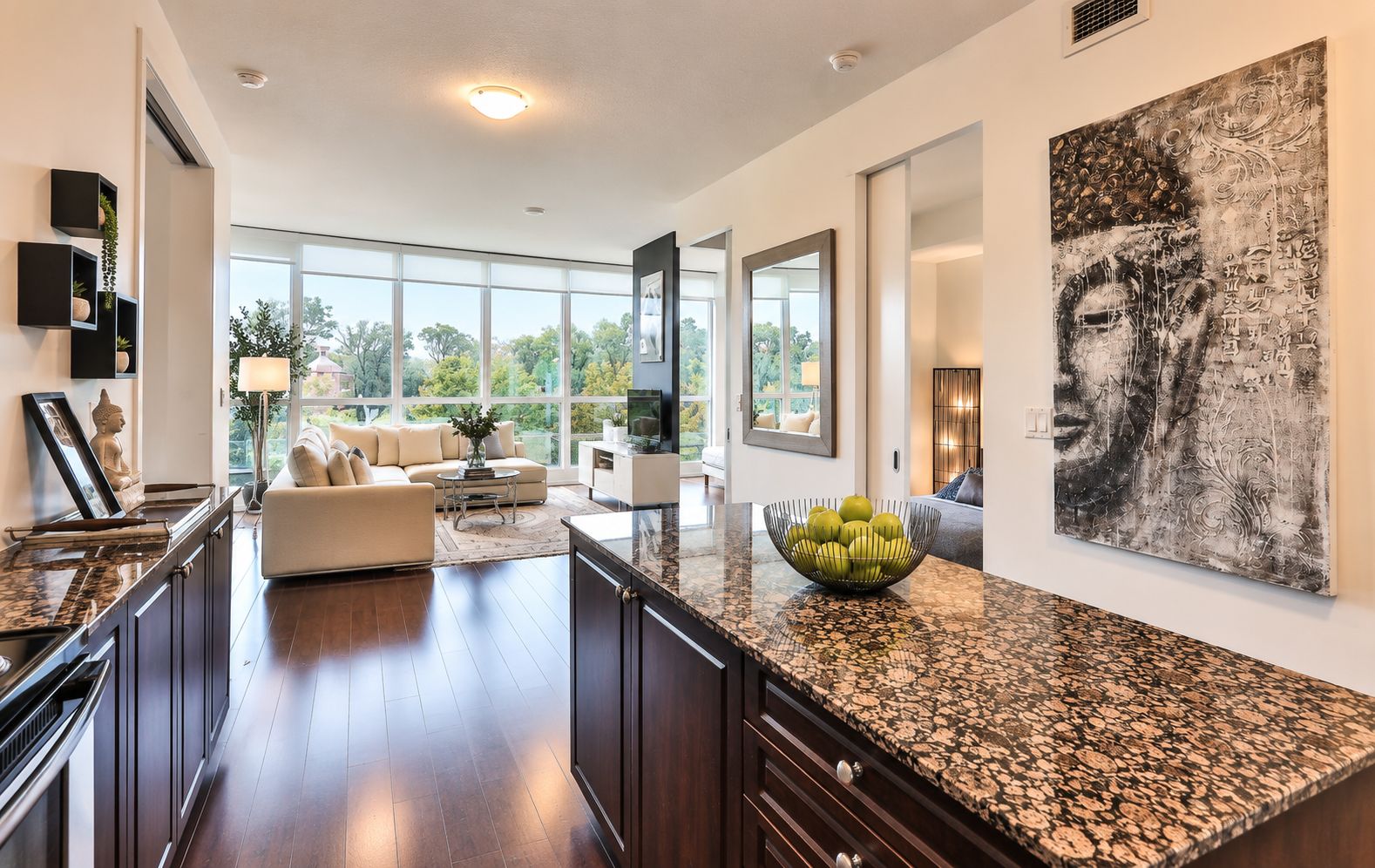 A modern kitchen with dark wood cabinets, a granite countertop, and a large window offering a view of the outdoors.
