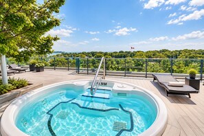 A hot tub with a view of a forest and a flag, surrounded by lounge chairs and potted plants. - Spectacular Presidential Loft - Downtown Toronto (Toronto)