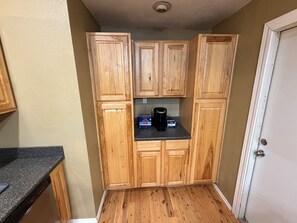 Une cuisine de taille réduite, avec des meubles de rangement en bois, un plan de travail et une machine à café.