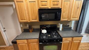 A kitchen with wooden cabinets, a black microwave, a gas stove, and a stainless steel dishwasher.
