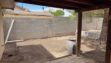 A covered outdoor area with a brick wall, a concrete planter, and a metal pipe.