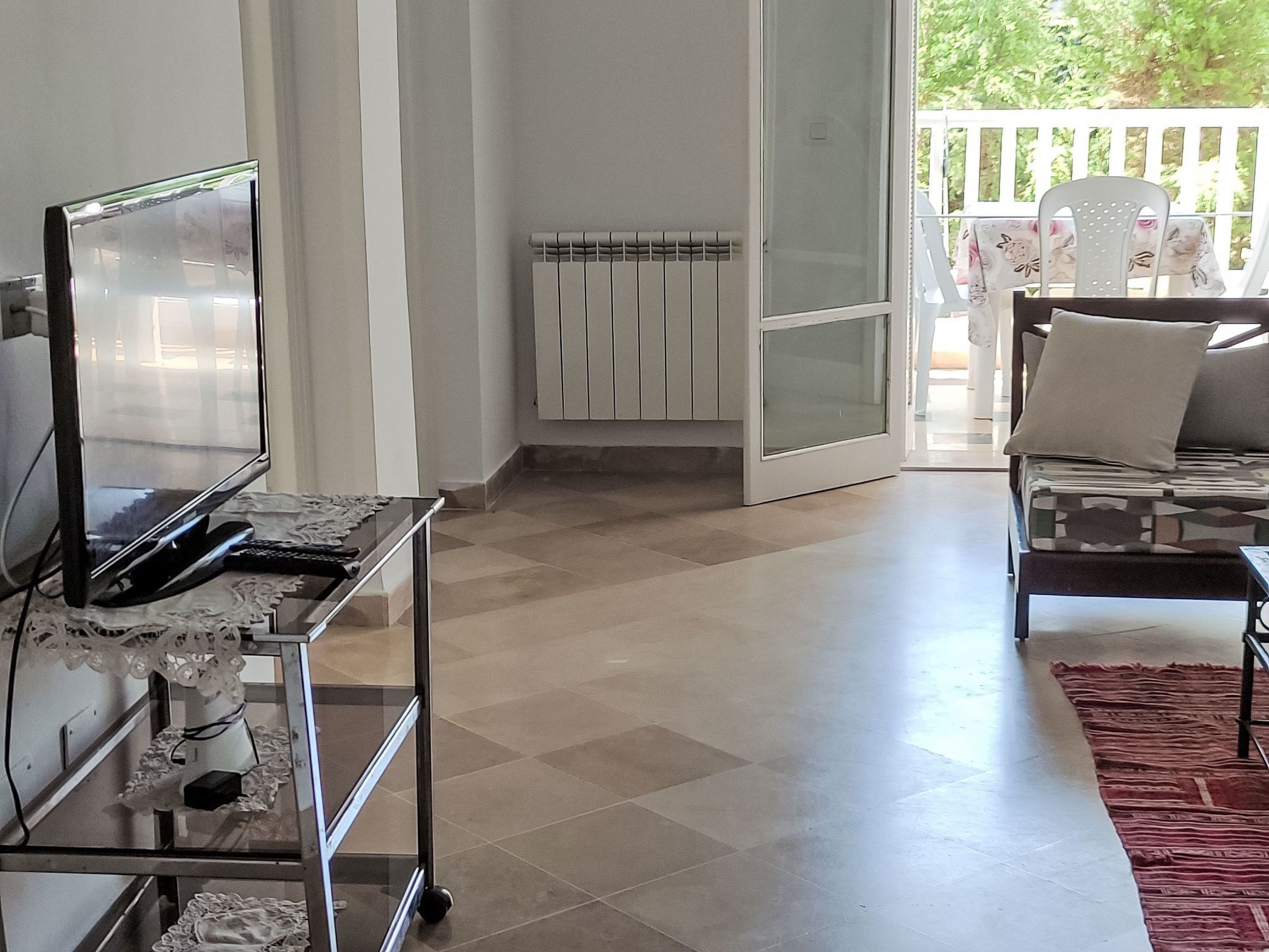 Un soggiorno con una televisione su un mobile, un termosifone e un divano con cuscini.