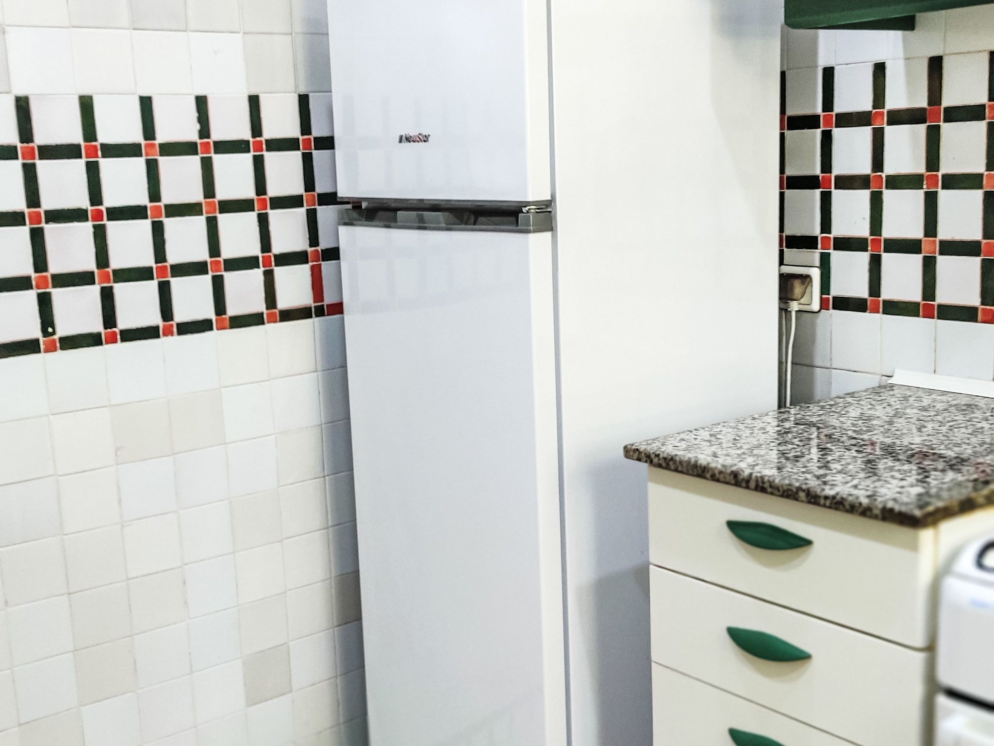 A kitchen with a white refrigerator, a tiled backsplash, and a granite countertop with a sink.