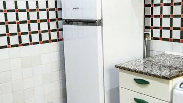 A kitchen with a white refrigerator, a tiled backsplash, and a granite countertop with a sink.