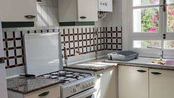 A kitchen with white cabinets, a gas stove, and a tiled backsplash.