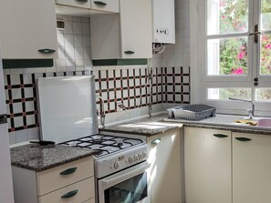 Una cucina con mobili bianchi, piano cottura a gas e rivestimento a piastrelle.